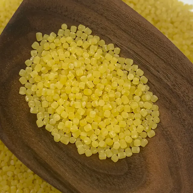 A close up shot of Acini di pepe in a wooden serving spoon