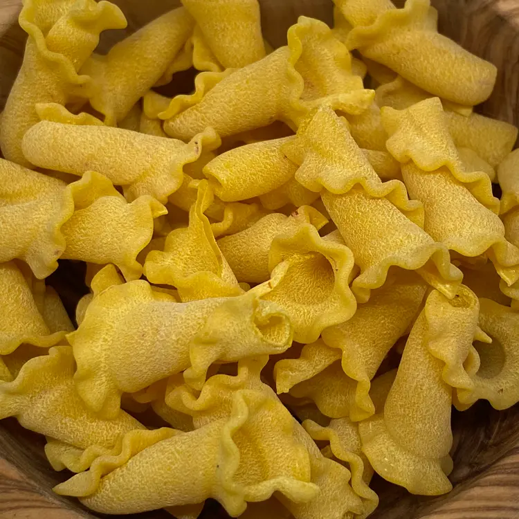 A close up shot of Campanelle in a round wooden bowl