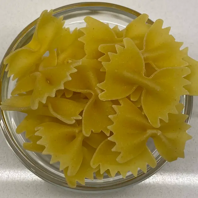 A close up shot of Farfalle in a clear round glass bowl