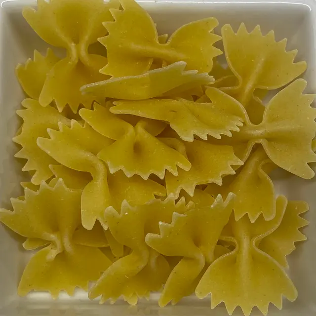 A close up shot of Farfalle in a square white glass bowl