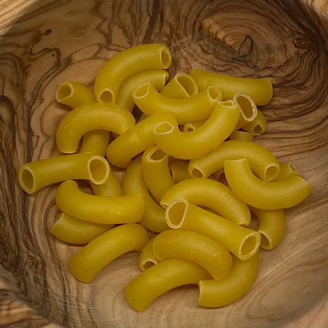 A close up shot of Large Elbow Macaroni in a round wooden bowl