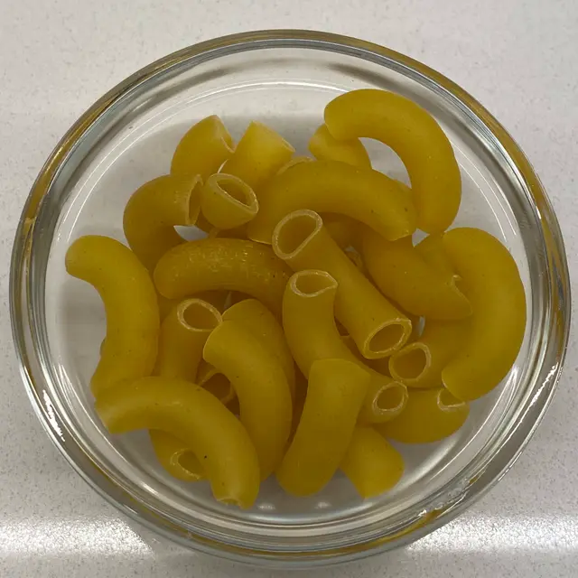 A close up shot of Large Elbow Macaroni in a small round white glass bowl