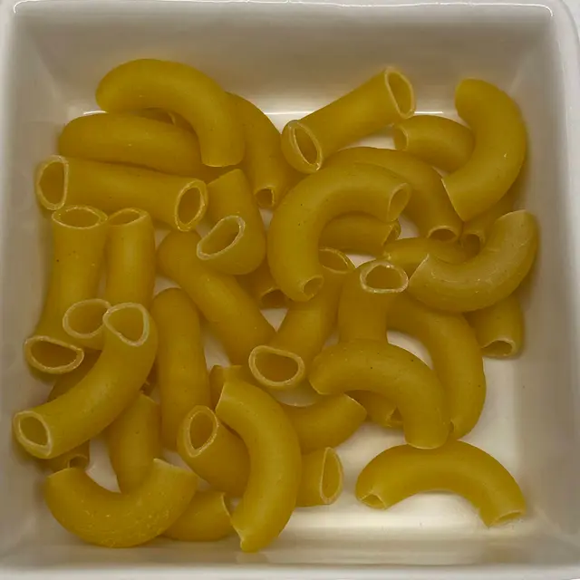 A close up shot of Large Elbow Macaroni in a square white glass bowl