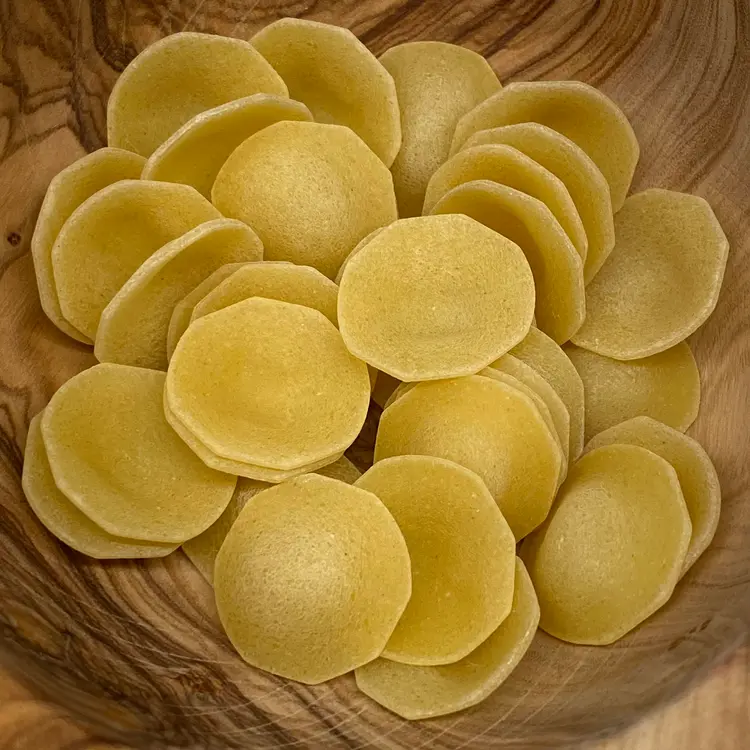 A close up shot of Orecchiette in a round wooden bowl