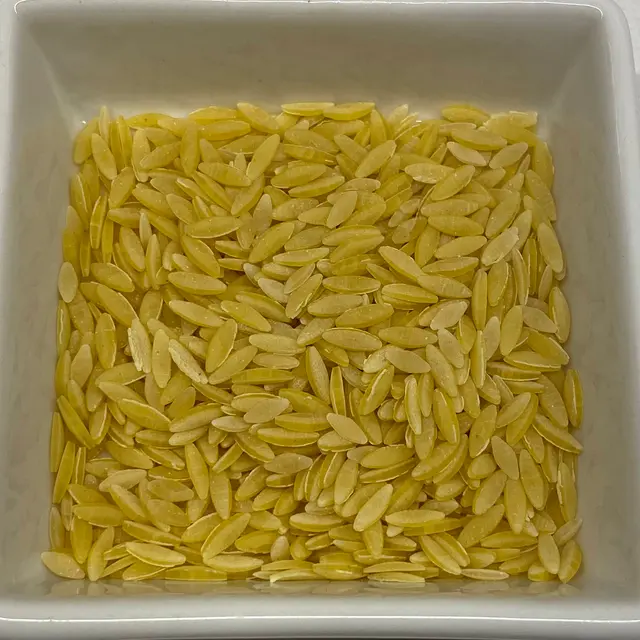A close up shot of Orzo in a square white glass bowl