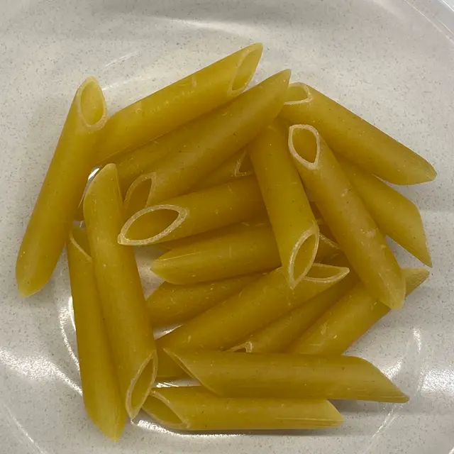 A close up shot of Penne in a clear round glass bowl