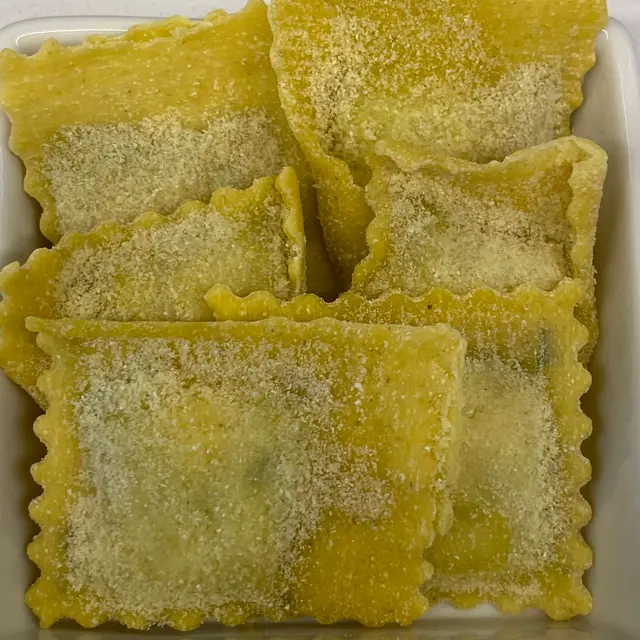 A close up shot of Ravioli in a square white glass bowl