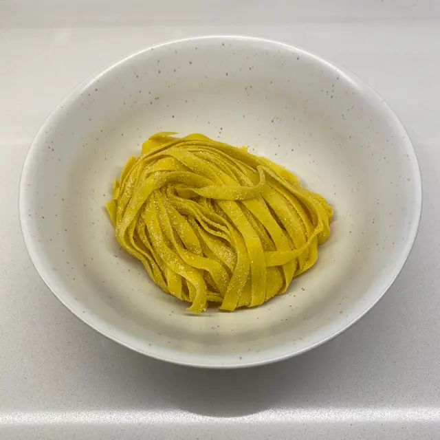 Tagliatelle in a speckled white bowl