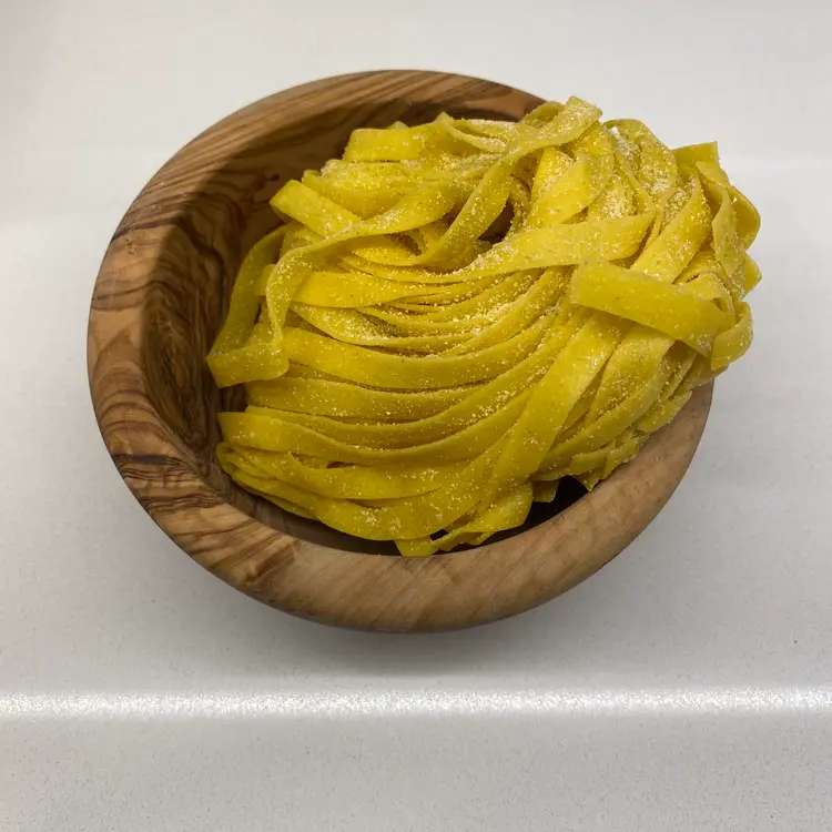 Tagliatelle in a round wooden bowl
