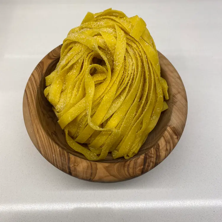 Tagliatelle in a round wooden bowl
