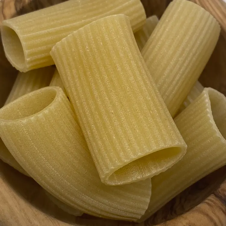 A close up shot of Paccheri in a round wooden bowl